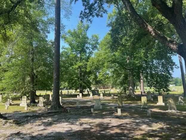 Weathered headstones under tall pines and oaks in a cemetery aboard Marine Corps Base Camp Lejeune, North Carolina